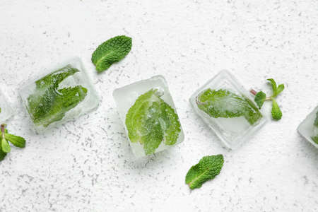 Fresh mint leaves frozen in ice on light backgroundの写真素材