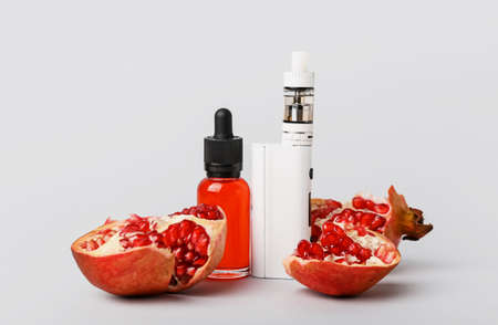 Modern vape mod, oil and pomegranate on gray background
