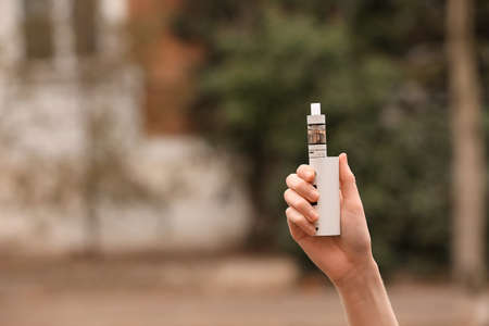 Female hand with modern vape mod outdoors