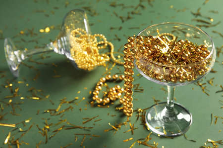Champagne glasses with golden beads and confetti on green backgroundの写真素材