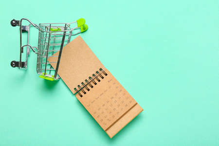Craft calendar and shopping cart on color backgroundの写真素材