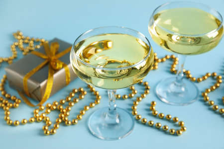 Glasses of champagne, beads and gift box on blue backgroundの写真素材