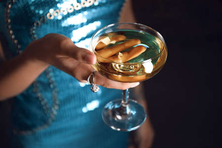 Woman in beautiful dress holding glass of champagne on dark background, closeupの写真素材