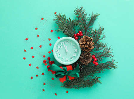 Stylish alarm clock, fir branches and Christmas decor on green backgroundの写真素材