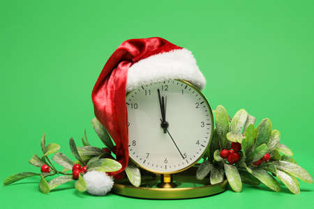 Alarm clock in Santa hat and decor on green backgroundの写真素材