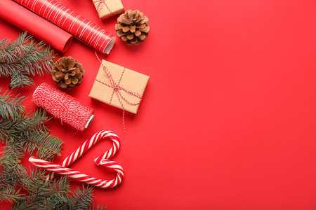 Composition with Christmas gift, fir branches and candy canes on red backgroundの写真素材