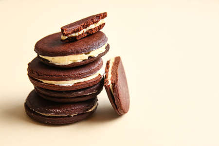 Tasty chocolate cookies with cream on beige background, closeup