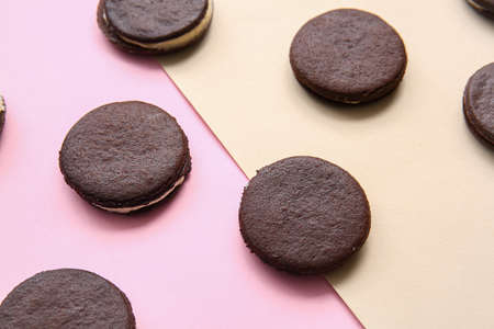 Tasty chocolate cookies with cream on color background, closeup