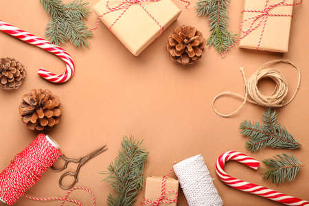 Frame made of Christmas gifts, candy canes, fir branches and pine cones on color background
