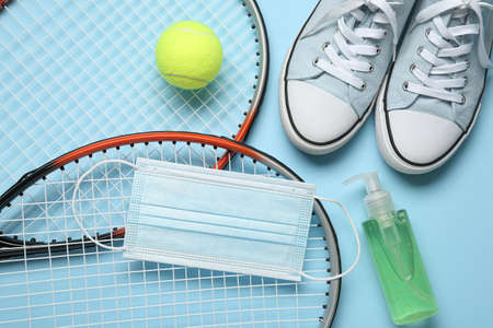 Tennis equipment, shoes, medical mask and bottle with antiseptic on color backgroundの写真素材