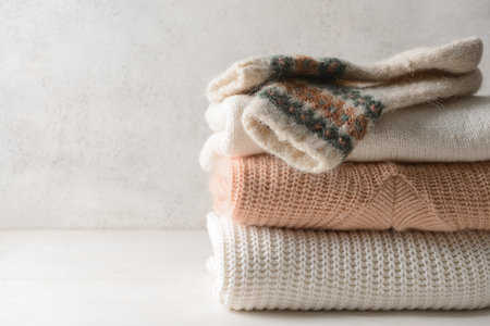 Stack of knitted sweaters and socks on white tableの写真素材