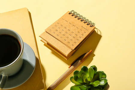 Craft calendar with notebook and cup of coffee on beige backgroundの写真素材