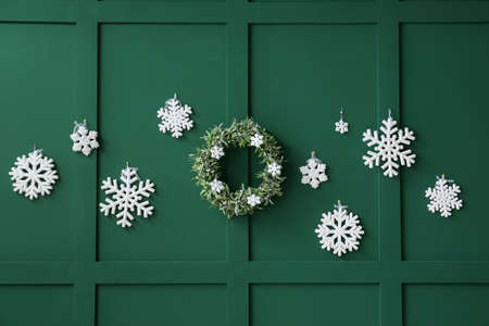 Beautiful snowflakes and Christmas wreath on green wall