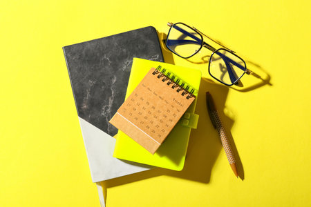 Craft calendar with notebooks and eyeglasses on yellow backgroundの写真素材