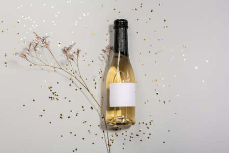 Bottle of champagne with confetti and branch on light backgroundの写真素材