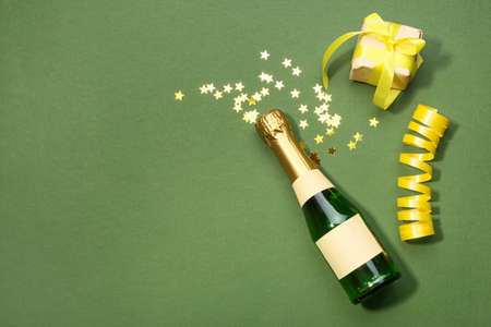 Bottle of champagne with confetti and gift on green backgroundの写真素材