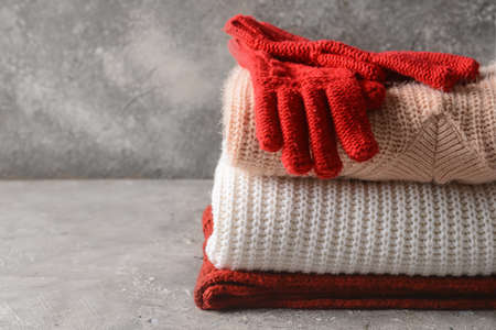 Stack of knitted sweaters and gloves on grunge backgroundの写真素材