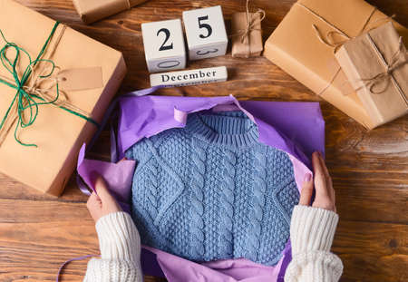 Woman unwrapping Christmas present on wooden background, closeupの写真素材