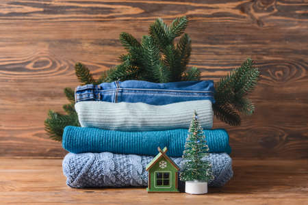 Stack of knitted sweaters and Christmas decor on wooden table