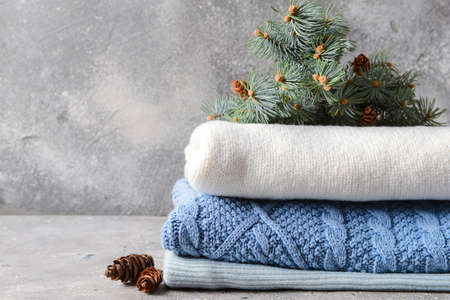 Stack of sweaters and fir tree branch on grunge backgroundの写真素材