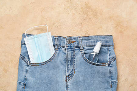 Stylish female jeans, medical mask and bottle with antiseptic on color backgroundの写真素材