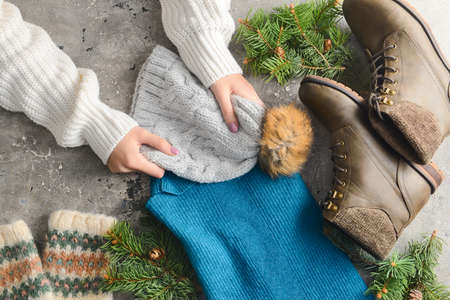 Female hands with warm clothes, shoes and fir tree branches on grunge background