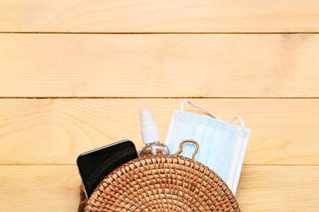 Wicker bag with mobile phone, antiseptic and medical mask on wooden backgroundの写真素材