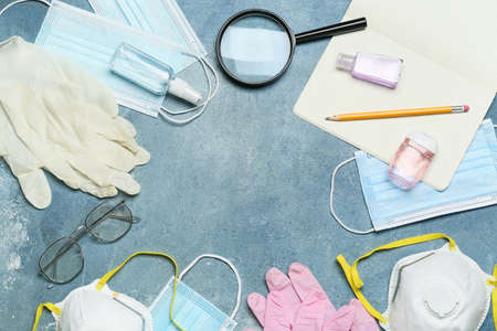 Frame made of stationery supplies, eyeglasses, magnifier, medical masks and gloves on color backgroundの写真素材