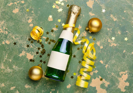 Bottle of champagne with Christmas decor on green background