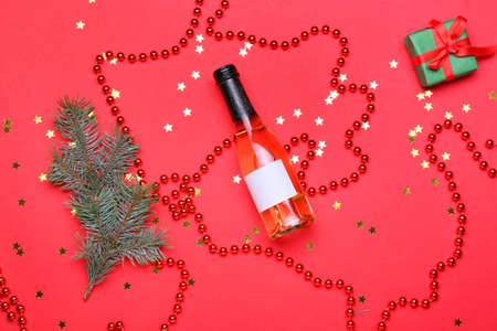 Composition with bottle of champagne and Christmas decor on red backgroundの写真素材