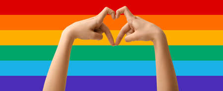 Woman making heart shape with her hands on rainbow background. LGBT conceptの写真素材