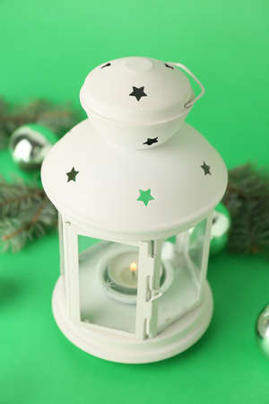 Beautiful Christmas lantern with burning candle on green backgroundの写真素材