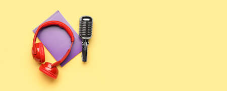 Headphones with microphone and notebook on yellow background with space for textの写真素材