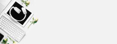 Tablet computer with headphones, keyboard and rose flowers on light background with space for textの写真素材