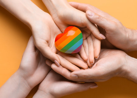 People holding rainbow heart on yellow background, top view. LGBT conceptの写真素材