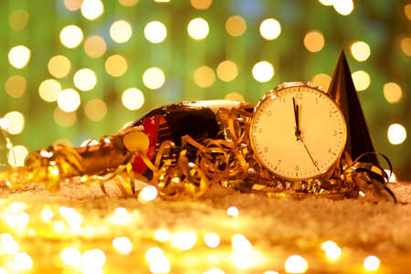 Stylish New Year clock, bottle of champagne and Christmas decor on table against blurred backgroundの写真素材