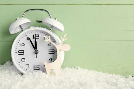 Stylish New Year clock, Christmas decor and snow on green wooden backgroundの写真素材