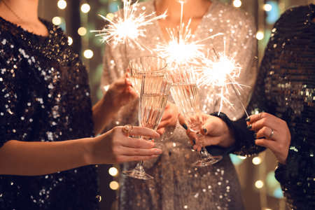 Women in elegant dresses with Christmas lights and glasses of champagne, closeupの写真素材