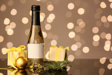Bottle of champagne, gift boxes and Christmas decor on table against blurred backgroundの写真素材