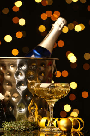 Bottle and glass of champagne with Christmas decor on table against blurred backgroundの写真素材
