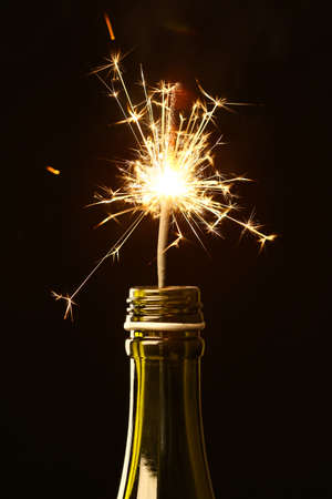 Bottle of champagne with Christmas sparkler on black background, closeupの写真素材