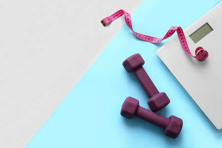 Dumbbells, measuring tape and scales on color backgroundの写真素材