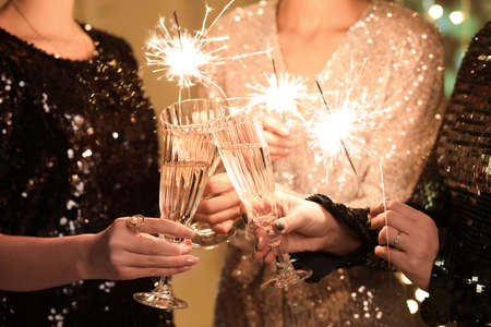 Women in elegant dresses with Christmas lights and glasses of champagne, closeupの写真素材