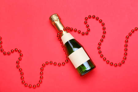 Bottle of champagne and beads on red backgroundの写真素材