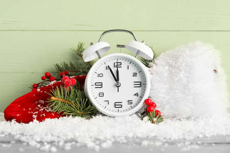 Stylish New Year clock, Christmas decor and snow on green wooden backgroundの写真素材