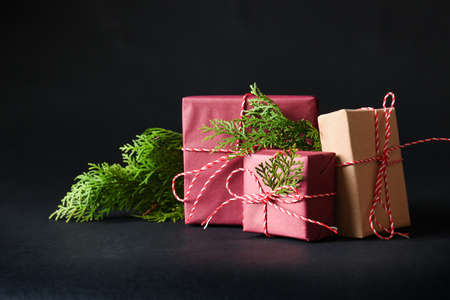 Beautiful Christmas gift boxes and fir branches on black background