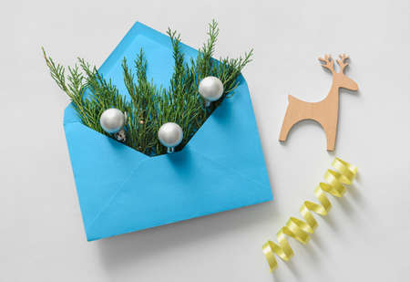 Composition with envelope, coniferous branches and Christmas decorations on white background