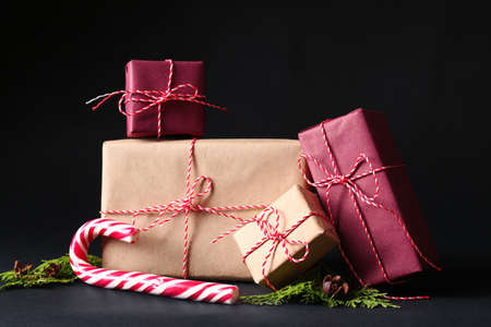 Beautiful Christmas gift boxes and candy cane on black background