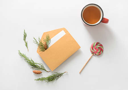 Composition with envelope, card, cup of tea and candy on white background