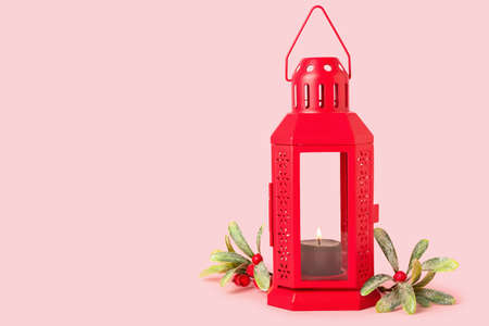 Christmas lantern with burning candle on pink backgroundの写真素材